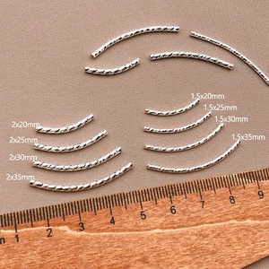 Detailed view of silver curved spacer beads with twisted texture in multiple sizes