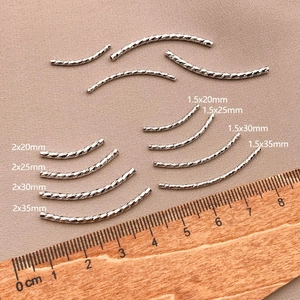 Detailed view of silver-plated twisted curved tube beads in various sizes for DIY jewelry