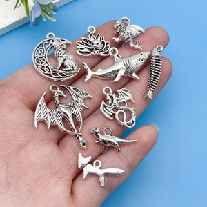 Close-up of vintage silver alloy charms featuring shark, dragon and dinosaur for DIY jewelry