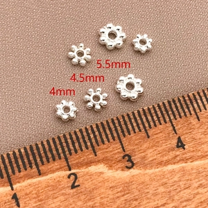 Vista macro di perle distanziatrici a fiocco di neve placcate oro 18K con righello per gioielli