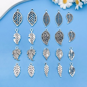 Set of vintage silver leaf alloy pendants for DIY jewelry making on blue background