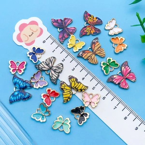 Vue détaillée de pendentifs papillon colorés en alliage à côté d'une règle de mesure