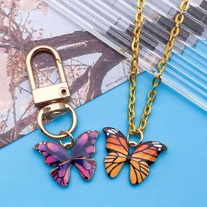 Détail des pendentifs papillons en émail sur collier doré et accessoire porte-clés