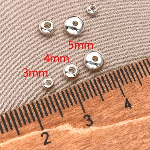 Vista macro de cuentas de metal plateado pulido de 3mm 4mm 5mm para creación de joyas DIY