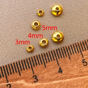 Detalle macro de cuentas bañadas en oro 18K de 3mm 4mm 5mm para creación de joyas