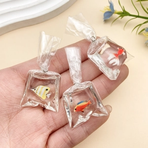Close-up of miniature resin goldfish water bag charms held in hand for DIY jewelry making