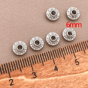 Macro shot of 6mm silver saucer spacer beads with detailed relief pattern for jewelry DIY