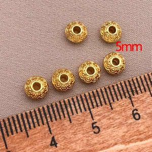 Detailed macro view of 5mm 18K gold-plated spacer beads with intricate spiral floral patterns