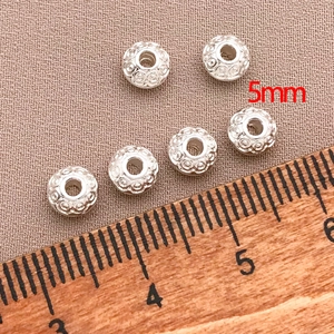 Close-up of 5mm silver saucer beads with vintage patterns for DIY jewelry making