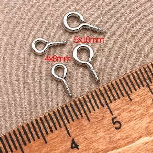 Detail of 4x8mm and 5x10mm silver eye pin screws with a wooden scale ruler