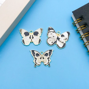 Detailed view of three gothic skull butterfly charms with black and white enamel drip