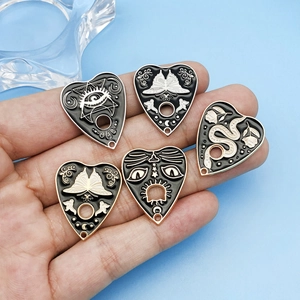 Detailed macro view of gothic heart charms featuring butterfly, snake, and mystical eye motifs