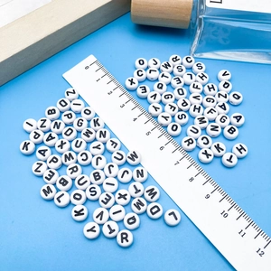 Platte ronde witte acryl alfabet kralen met zwarte letters en een liniaal