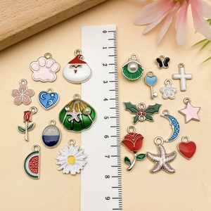 Macro view of assorted enamel flower and butterfly charms with ruler for size scale