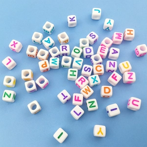 Vista macro de cuentas de cubo de 6mm en acrílico blanco con letras de colores para bisutería