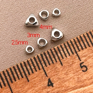 Vue macro de perles d'espacement triangulaires plaquées or 18k avec échelle de taille