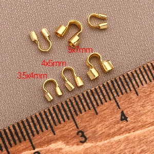 Macro shot of 18K gold plated U-shape wire guards in three sizes on a measuring ruler