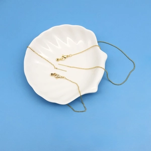 Details einer verstellbaren goldenen Kugelkette mit Karabiner auf einer Schale