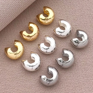 Gold and silver C-shaped moon beads for DIY jewelry making displayed on a textured fabric