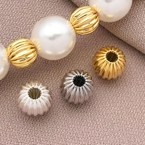 Vista macro de cuentas espaciadoras de calabaza bañadas en oro 18K para joyería DIY