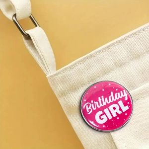 Gros plan d'un badge en fer-blanc rose Birthday Girl sur un sac en toile blanc