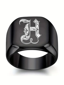 Détail macro d'une bague chevalière gothique en acier noir avec lettre H gravée