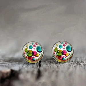 Orecchini a perno in vetro con pois colorati su sfondo di legno grigio texture