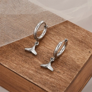 Elegante Ohrringe aus Edelstahl mit Fischschwanz-Motiv auf Holz- und Netz Hintergrund