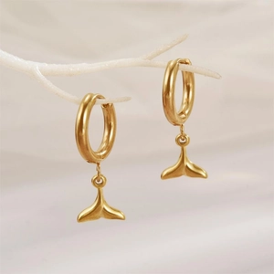 Elegante goldene Fischschwanz-Ohrringe aus Edelstahl auf einem weißen Ast präsentiert