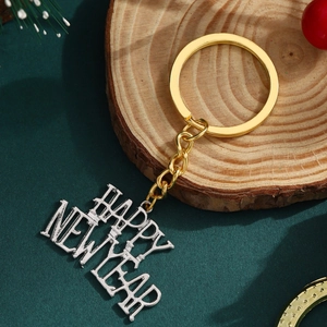 Golden and silver Happy New Year metal keychain with festive pine and berry background