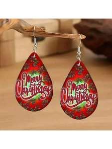 Détail de boucles d'oreilles de Noël rouges en forme de goutte sur une branche en bois