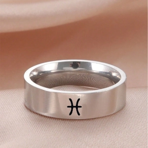 Makroaufnahme eines silbernen Pisces Sternzeichen-Rings auf rosa Seidenstoff