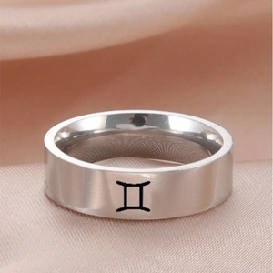 Makroaufnahme des silbernen Gemini-Sternzeichenrings aus Edelstahl auf Champagner-Satin