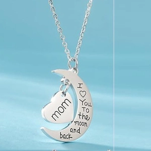 Macro detail of crescent moon and heart pendant engraved with I love you to the moon and back