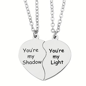 Detail view of puzzle heart necklaces with engraved You're my Shadow and Light text