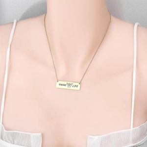 Close-up of golden Pogue Life engraved bar pendant necklace on female model