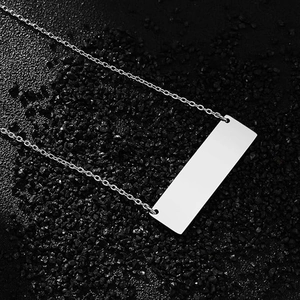 Macro top view of polished silver rectangle pendant necklace on black textured stone background