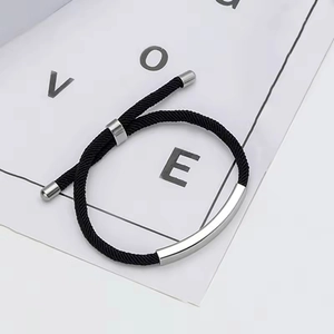 Dettaglio di un bracciale di coppia intrecciato nero con barra in acciaio inossidabile
