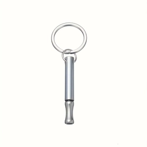 Close-up of polished silver stainless steel meditation whistle on a metal keyring