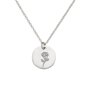 Dettaglio macro di una collana d'argento minimalista con ciondolo circolare inciso a fiori