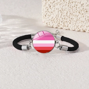 Macro detail of lesbian pride glass cabochon charm on adjustable black braided bracelet