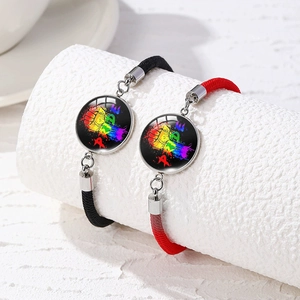 Detail of woven rainbow pride bracelets in black and red with metal charm