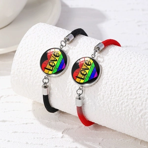 Macro shot of hand-woven bracelets featuring rainbow hearts and LOVE letter pendants