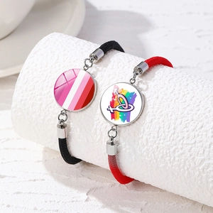 Detail of hand-woven LGBTQ+ Pride bracelets with rainbow glass pendants on white pillars
