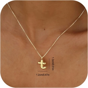 Nahaufnahme von goldenem Buchstaben-T-Anhänger mit Maßen und Kreuzkette am Hals