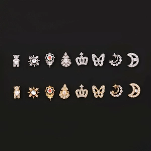 Macro view of geometric bow, crown, and moon stud earrings set with zircon stones