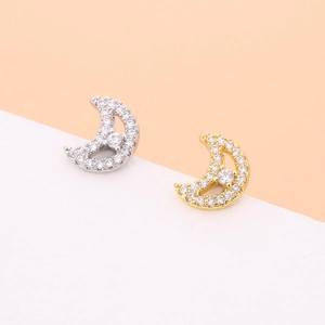 Close-up of gold and silver moon earrings with sparkling cubic zirconia on white stand