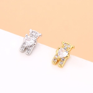 Macro shot of bear-shaped studs with heart-shaped zircon in gold and silver plating