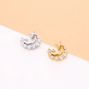 Macro view of gold and silver crescent moon earrings with cubic zirconia inlay and star