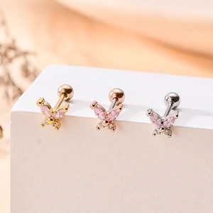 Macro shot of butterfly cartilage earrings with pink zircon wings in gold, rose gold and silver